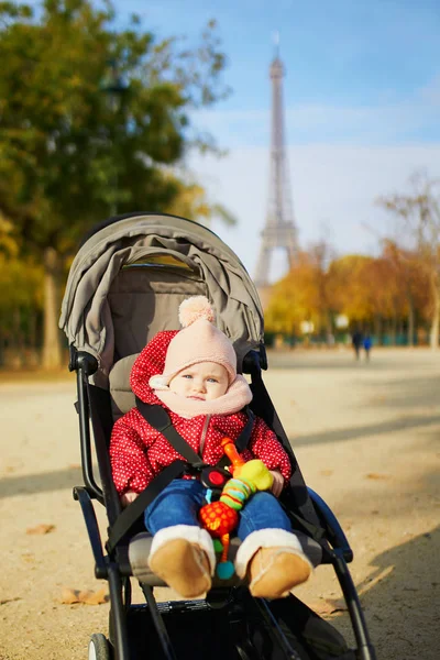 Fille en vêtements élégants lumineux assis en poussette à l'extérieur un jour d'automne — Photo