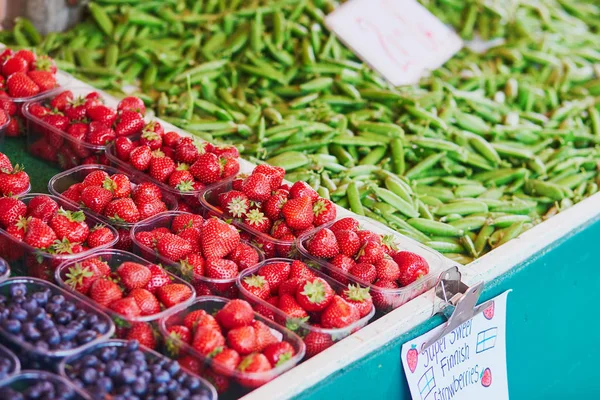 Fragole fresche, piselli verdi e mirtilli in vendita sul mercato alimentare locale — Foto Stock