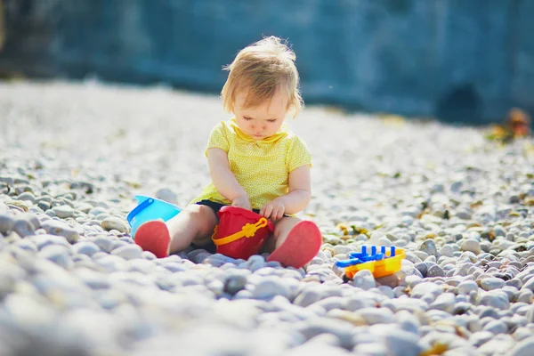 Αξιολάτρευτο νήπιο κορίτσι που παίζει με βότσαλα στην παραλία — Φωτογραφία Αρχείου