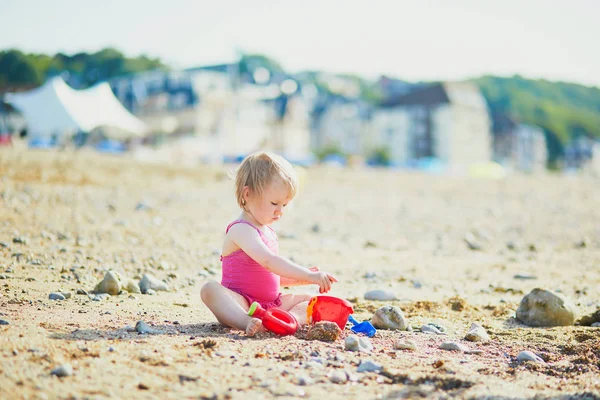 Roztomilé batole dívka si hraje s pískem na pláži — Stock fotografie