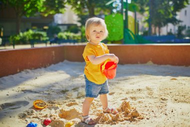 küçük kız kum havuzunda oyun alanında eğleniyor