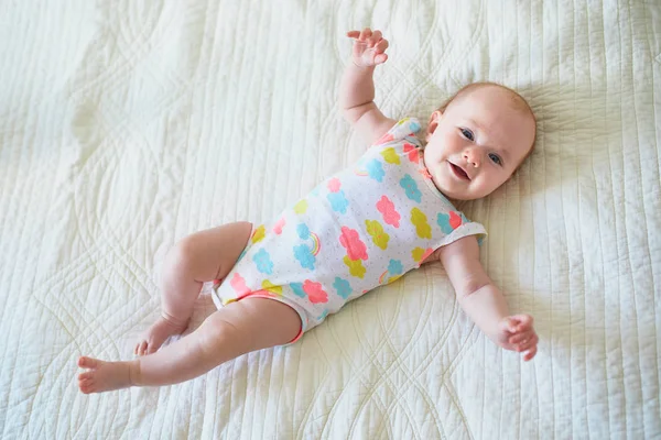 Babymeisje liggend op bed en glimlachen — Stockfoto