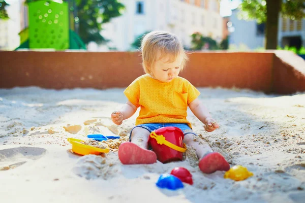 Klein meisje met plezier op speelplaats in zandbak — Stockfoto