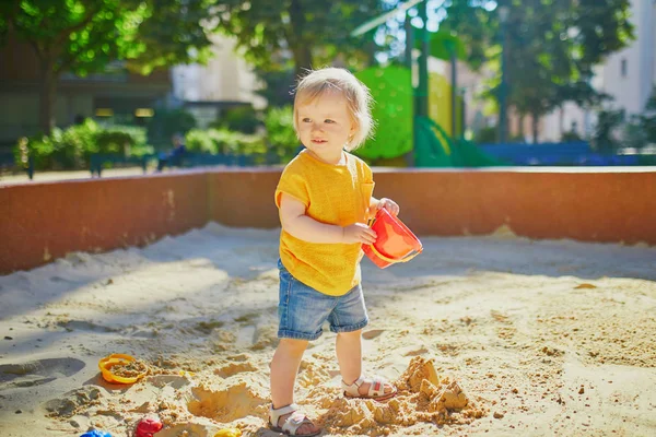 Klein meisje met plezier op speelplaats in zandbak — Stockfoto