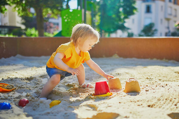 little girl having fun on playground in sandpit