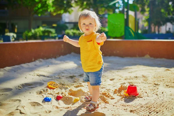 Klein meisje met plezier op speelplaats in zandbak — Stockfoto