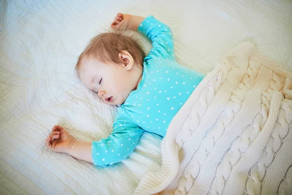 Adorável bebê menina dormindo no berço sob cobertor de malha — Fotografia de Stock