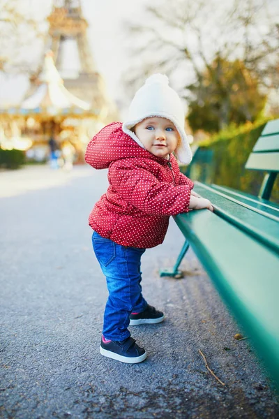 Holčička stojí na ulici a drží se na lavičce. — Stock fotografie