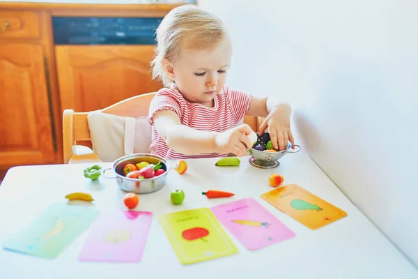 Bedårande liten flicka leker med leksaks frukter och grönsaker — Stockfoto