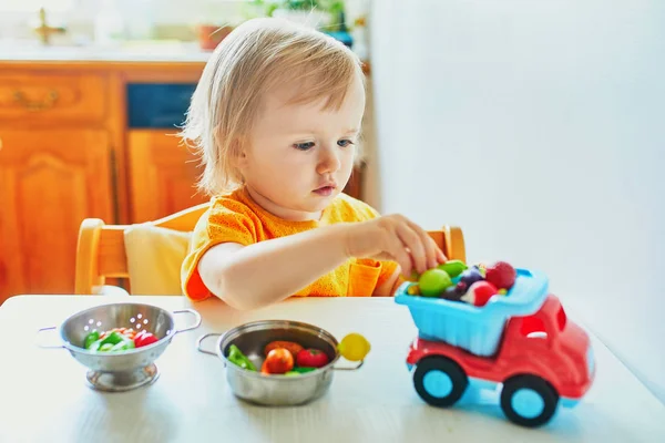 Urocza mała dziewczynka gra z owocami i warzywami zabawek — Zdjęcie stockowe