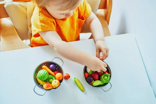 Urocza mała dziewczynka gra z owocami i warzywami zabawek — Zdjęcie stockowe