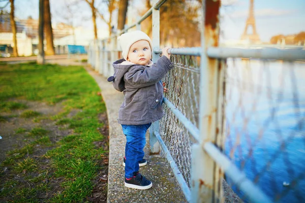 Niña de un año parada junto a valla metálica en el parque — Foto de Stock