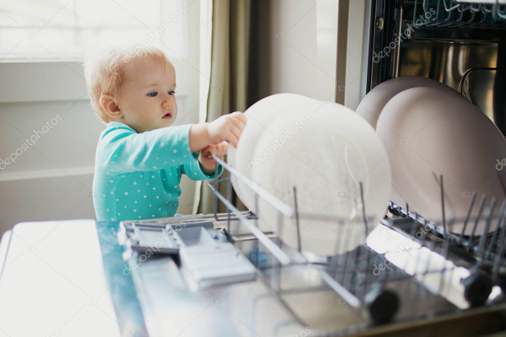 Little child helping to unload dishwasher