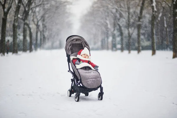 Glücklich lächelndes kleines Mädchen im Kinderwagen in Paris Tag mit starkem Schnee — Stockfoto