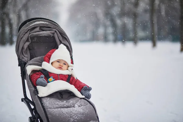 Glad leende Baby flicka i sittvagn i Paris dag med tung snö — Stockfoto