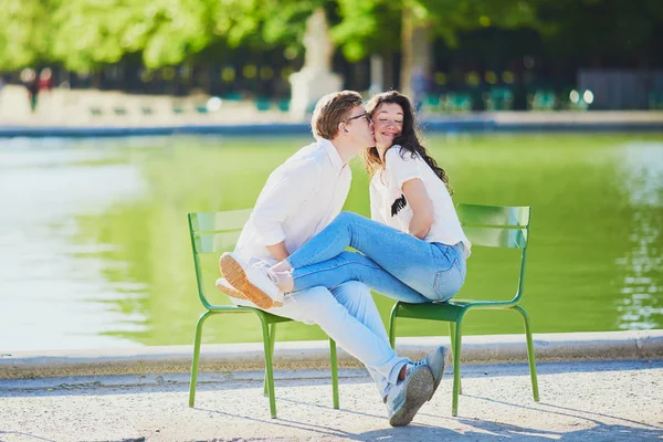 Happy romantic couple in Paris, sitting on traditional green metal chairs in Tuileries garden