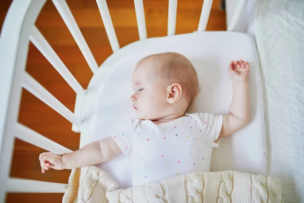 Baby sleeping in co-sleeper crib attached to parents\' bed