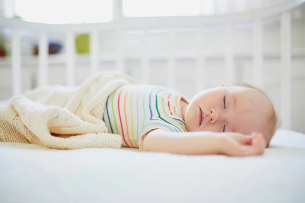 Baby sleeping in co-sleeper crib attached to parents 'bed — стоковое фото