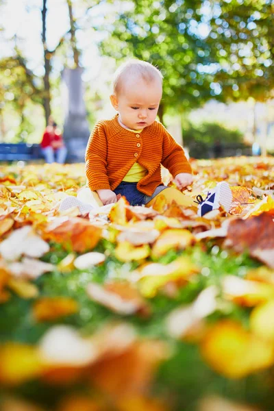 Entzückendes kleines Mädchen spielt mit gelben Herbstblättern — Stockfoto