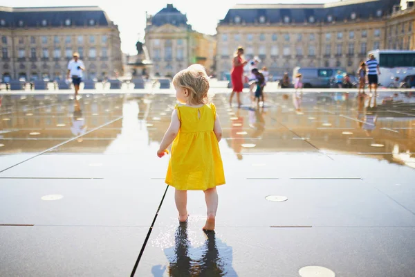 Kleinkind-Mädchen mit Spaß berühmten Outdoor-Brunnen (miroir d 'eau) in Bordeaux — Stockfoto