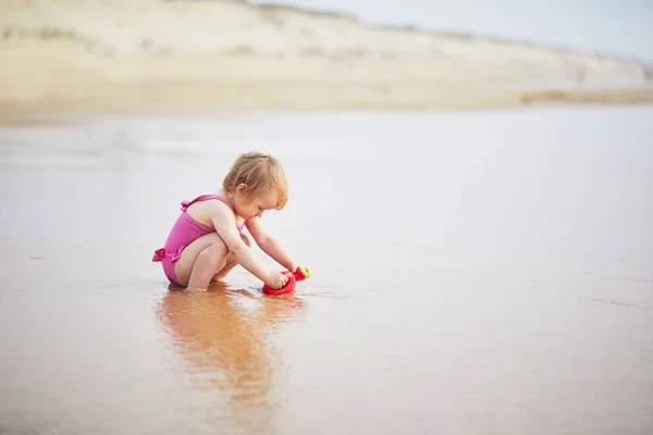 Flicka leker med röd vattenkanna på havet stranden — Stockfoto