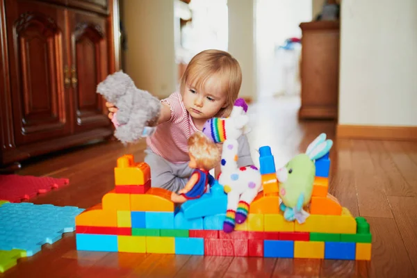 Очаровательная маленькая девочка играет с красочными пластиковыми блоками — стоковое фото