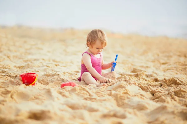 Κορίτσι παίζει με άμμο στην παραλία — Φωτογραφία Αρχείου