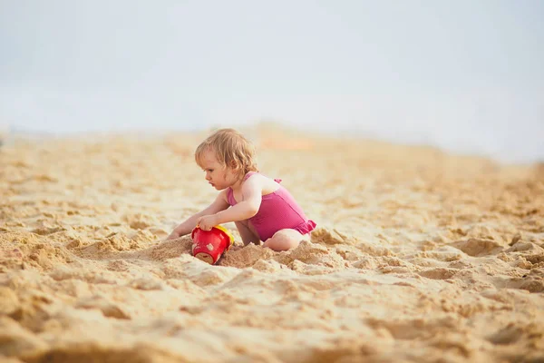 Κορίτσι παίζει με άμμο στην παραλία — Φωτογραφία Αρχείου