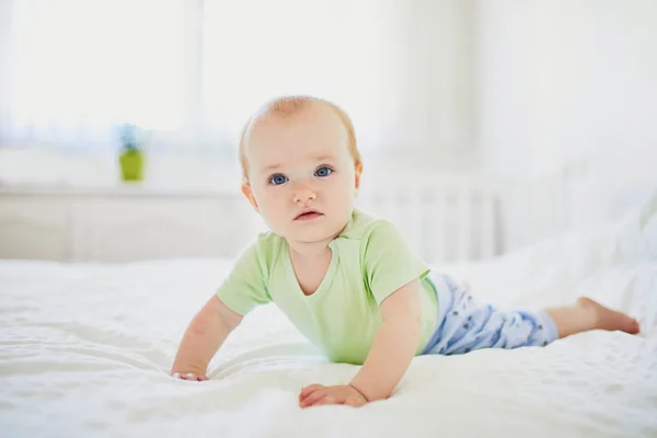 Bebé niña arrastrándose en la cama y riendo — Foto de Stock