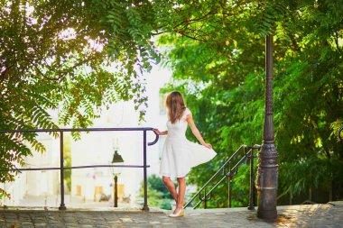 woman in white dress walking on famous Montmartre hill in Paris