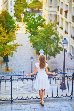 woman in white dress walking on famous Montmartre hill in Paris
