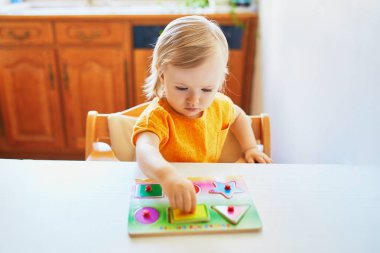 Sevimli yürümeye başlayan kız ahşap bulmaca yapıyor