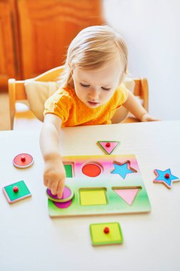 Sevimli yürümeye başlayan kız ahşap bulmaca yapıyor