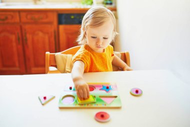 Sevimli yürümeye başlayan kız ahşap bulmaca yapıyor