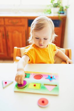 Sevimli yürümeye başlayan kız ahşap bulmaca yapıyor