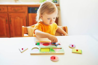 Sevimli yürümeye başlayan kız ahşap bulmaca yapıyor