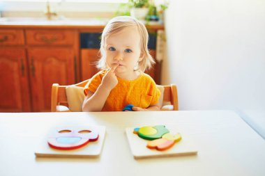 Sevimli yürümeye başlayan kız ahşap bulmaca yapıyor
