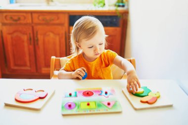 Sevimli yürümeye başlayan kız ahşap bulmaca yapıyor