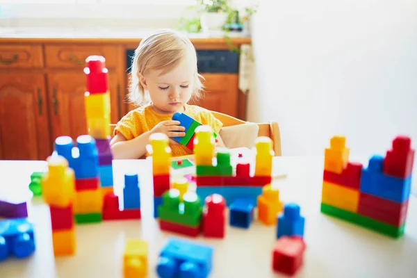 Liten flicka som leker med färgglada plast byggstenar — Stockfoto