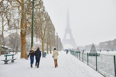 Paris'te karlı bir günde şemsiyelerle yürüyen insanlar