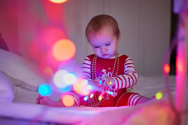 Joyeux bébé fille en pyjama jouant avec les décorations de nouvel an arbre — Photo