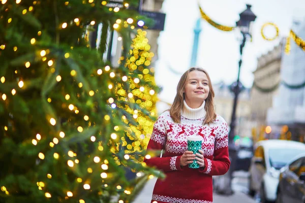 뜨거운 음료와 함께 걷는 소녀는 크리스마스를 위해 장식 된 파리의 거리에 가기 위해 — 스톡 사진