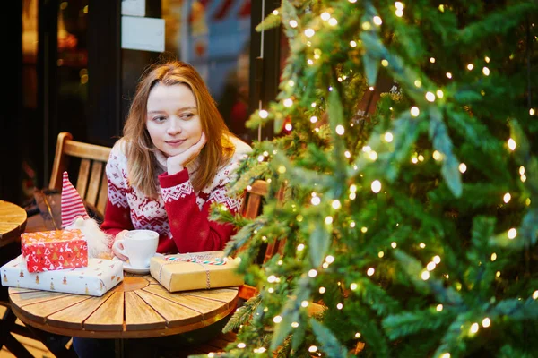 Meisje in vakantie trui drinken van koffie of warme chocolademelk in Café ingericht voor Kerstmis — Stockfoto