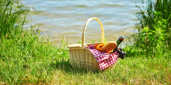 Cesta de piquenique com comida perto da água — Fotografia de Stock