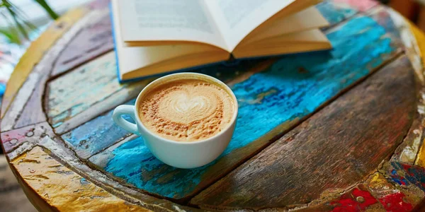 Cup of coffee and book on a wooden table — Stock Photo, Image