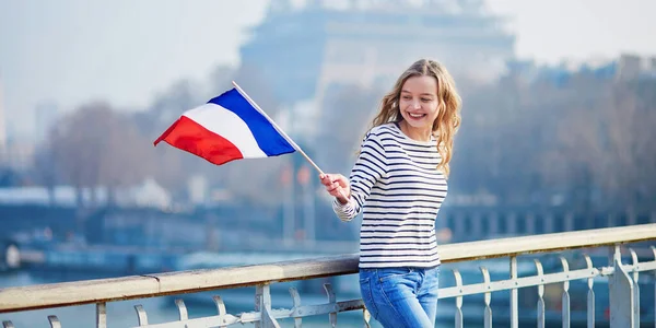 Krásná mladá dívka s francouzskou národní vlajkou nedaleko Eiffelovy věže — Stock fotografie