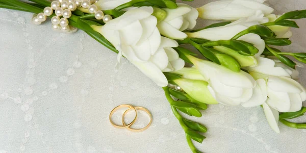 Dva zlaté prsteny se svatebním závojem a květy — Stock fotografie