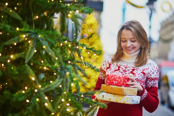 크리스마스 선물의 더미와 휴일 스웨터에 행복한 어린 소녀 — 스톡 사진