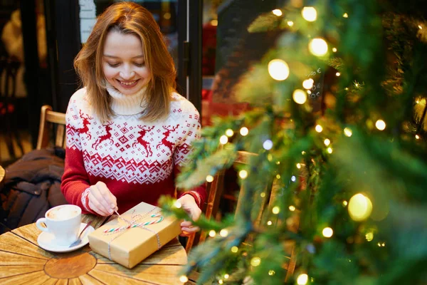 Κορίτσι σε πουλόβερ διακοπών πίνοντας καφέ ή ζεστή σοκολάτα σε καφέ διακοσμημένο για τα Χριστούγεννα — Φωτογραφία Αρχείου