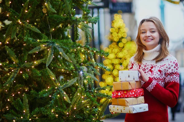 快乐的年轻女孩在节日毛衣与一堆圣诞礼物 — 图库照片